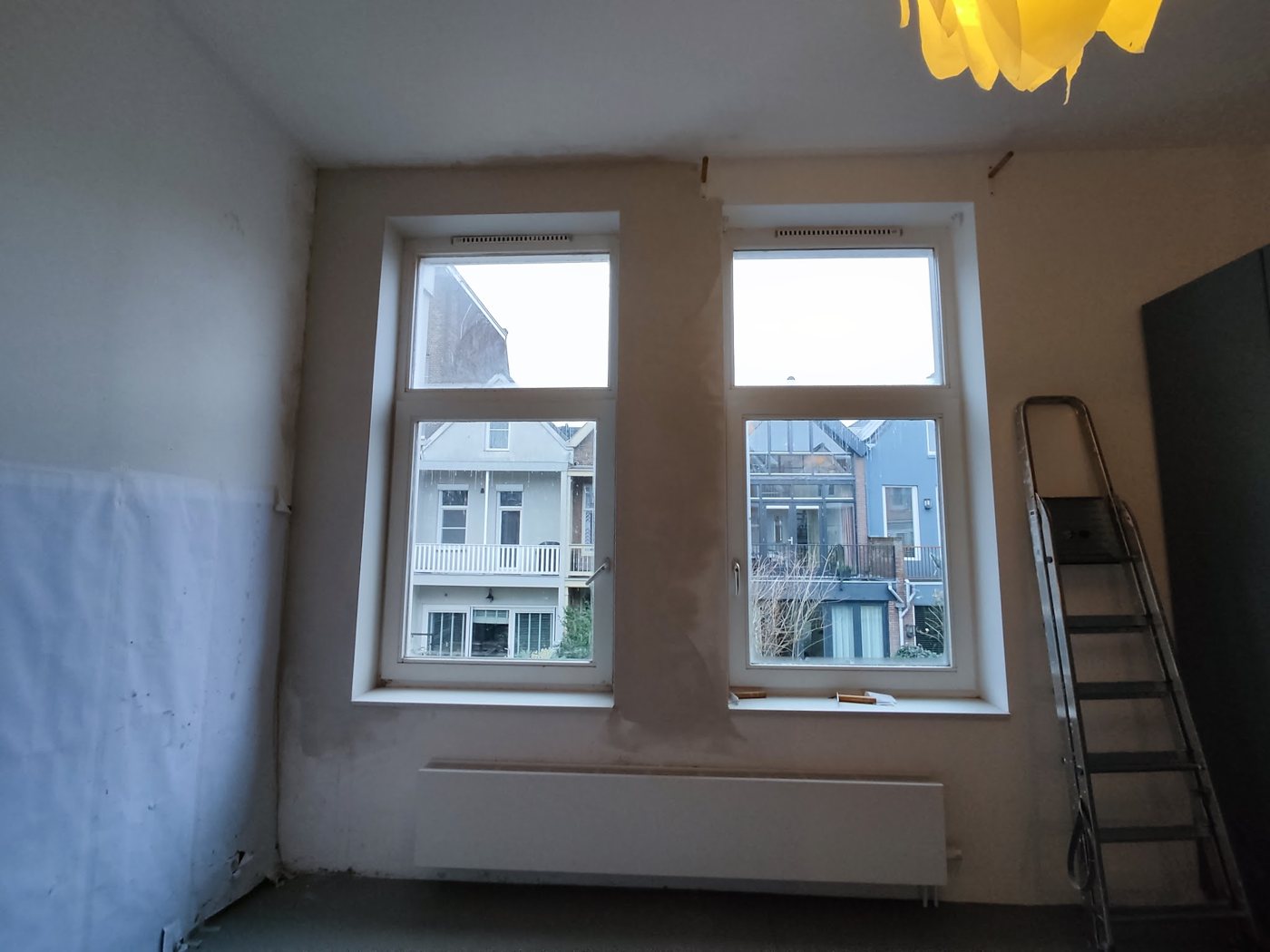 Lege kamer met vers voorbereide wanden, twee ramen en een trapje